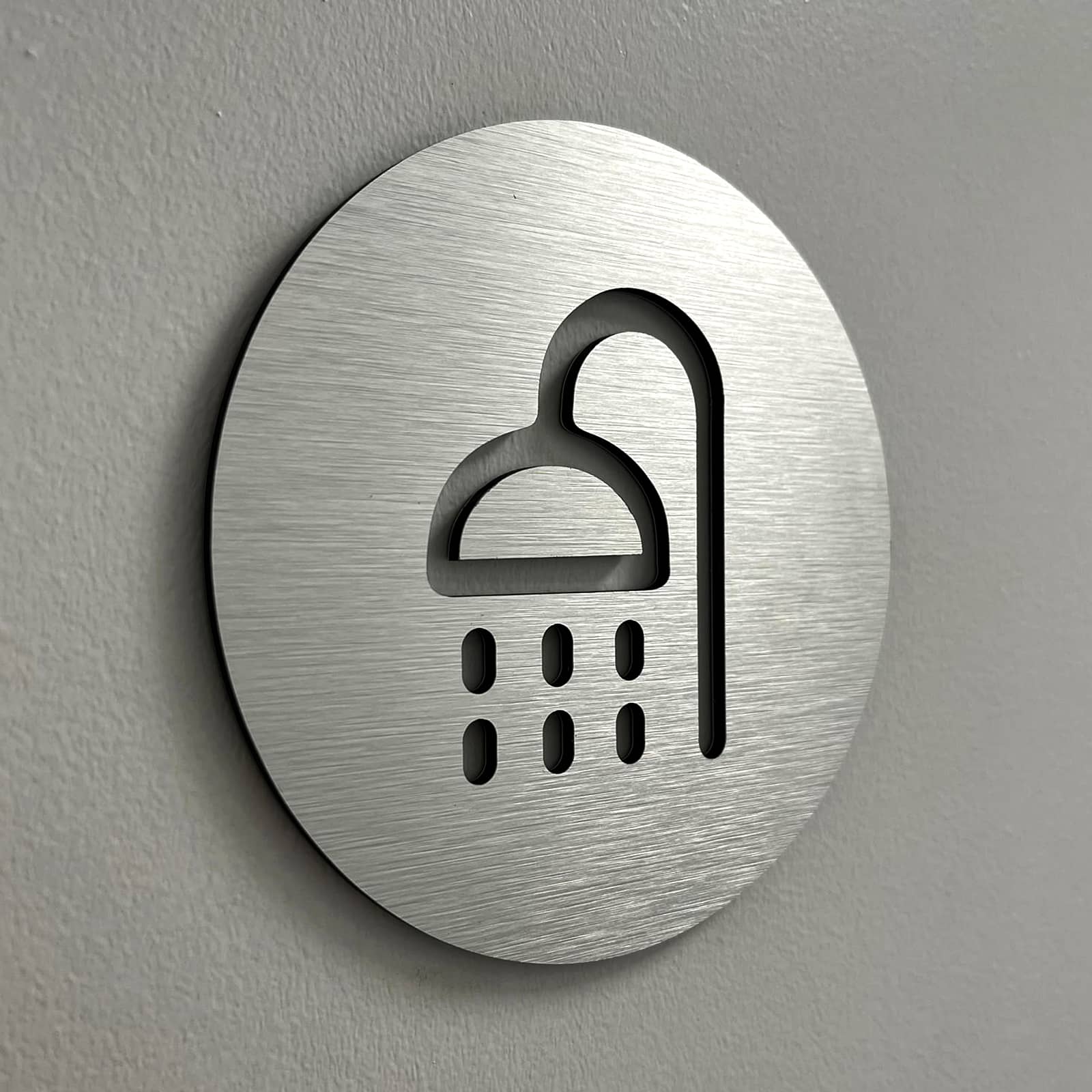détail décoratif avec un picto douche gravé dans une signalétique en acier brossé