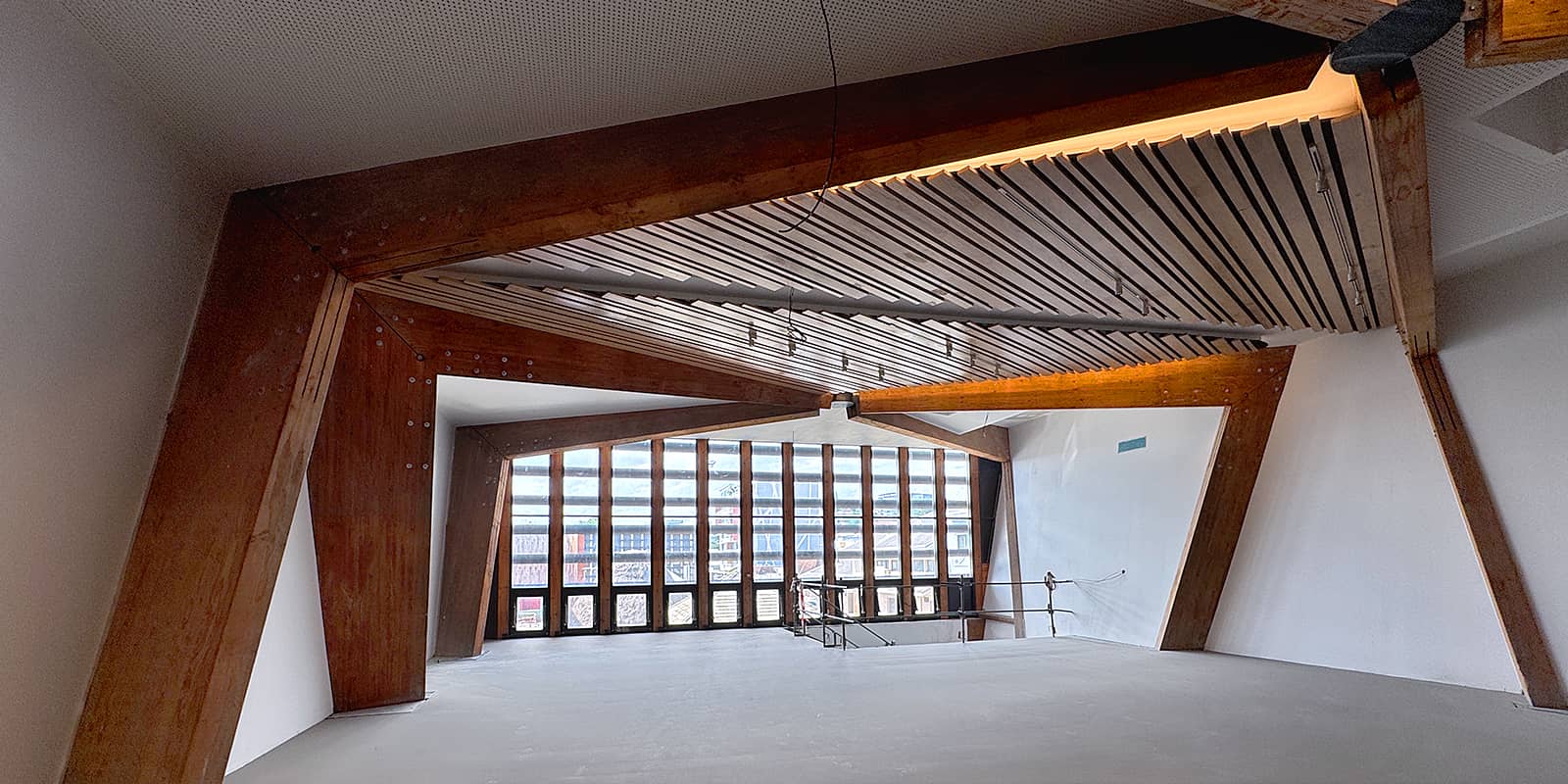 vue large de l'intérieur, avec les charpentes massives en bois et la lumière traversant par la verrière